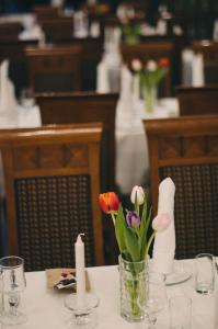 a table with a vase of flowers and candles on it at Grand Hotel H&oslash;nefoss in H&oslash;nefoss