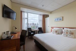 Cette chambre comprend un lit, un bureau et une fenêtre. dans l'établissement Aquarius Hotel, à Scheveningen