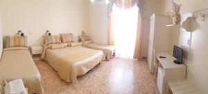 a white bedroom with two beds and a television at RS San Sebastiano Holidays in Acireale