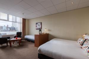 a hotel room with two beds and a desk at Aquarius Hotel in Scheveningen