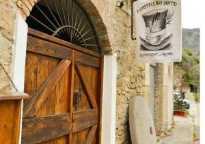una porta per un edificio con un cartello e una tavola da surf di Il Cappellaio Matto a Montalto Ligure