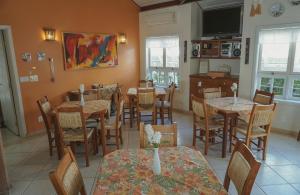 a dining room with tables and chairs and a tv at Alambari Village in Alambari