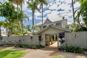 a house with a white fence and palm trees at Seascape Holidays at The Queenslander in Port Douglas