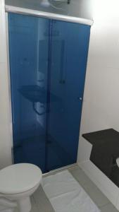 a white toilet sitting in a bathroom next to a blue wall at Pousada Victoria Reggia in São Sebastião
