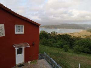 een rood huis met uitzicht op een meer bij Casa acogedora con vistas al mar in Valdoviño