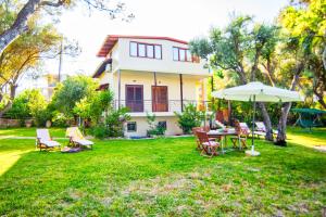 a yard with chairs and an umbrella and a house at Villa Spitaki in Nikiana
