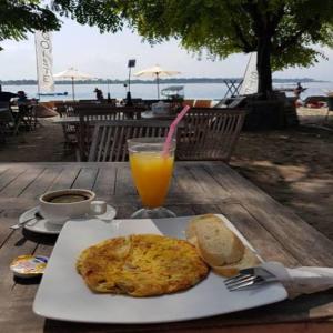 a table with a plate of food and a glass of orange juice at Dream Hotel in Gili Trawangan