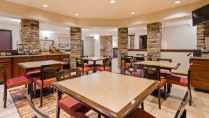 a restaurant with tables and chairs and a bar at SureStay Plus Hotel by Best Western Coffeyville in Coffeyville