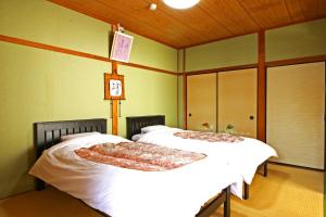 two beds in a room with green walls at Shirasakiso in Yura