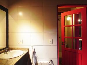 baño con lavabo y puerta roja en Sherpa Hostel en San Martín de los Andes