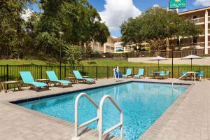 una piscina con sillas y mesas y un edificio en La Quinta by Wyndham Gainesville, en Gainesville