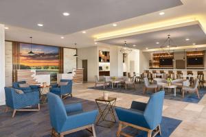 a lobby with chairs and tables and a bar at La Quinta Inn & Suites by Wyndham College Station North in College Station