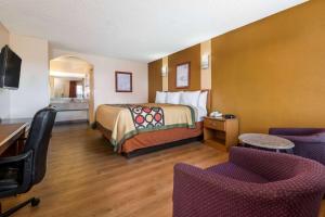 Pokój hotelowy z łóżkiem, biurkiem i krzesłami w obiekcie Super 8 by Wyndham Waco/Mall area TX w mieście Waco