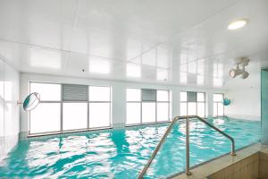 a large indoor swimming pool with blue water at Cityscape Charm Apt w Parking, Views, Pool & Gym in Auckland