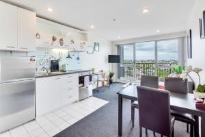 a kitchen with white appliances and a table with chairs at Cityscape Charm Apt w Parking, Views, Pool & Gym in Auckland