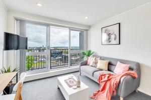 a living room with a couch and a large window at Cityscape Charm Apt w Parking, Views, Pool & Gym in Auckland