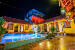 a villa with a swimming pool at night at Phong Nha Ecolodge in Phong Nha