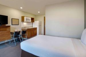 a bedroom with a bed and a kitchen with a refrigerator at WoodSpring Suites Washington DC Andrews AFB in Camp Springs