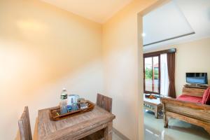 a room with a bed and a table and a television at Ashanti Villa Ubud in Ubud