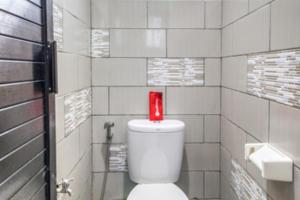 une bougie rouge au-dessus des toilettes dans une salle de bain dans l'établissement RedDoorz Hostel near Stadion Mandala Krida Yogya, à Yogyakarta