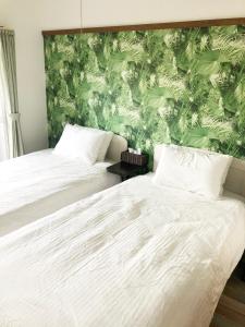 a bedroom with two beds and a green wall at ラ・ポート空港前201 in Fukuoka