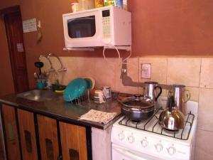 y cocina con fogones, microondas y fregadero. en Loma Tika - Tilcara Hostel en Tilcara