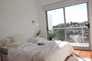 een witte slaapkamer met een bed en een groot raam bij Pátio da Achada View Apartment in Funchal
