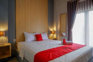 una habitación de hotel con una cama grande con almohadas rojas en RedDoorz Syariah @ Jalan Sultan Agung Tegal en Tegal