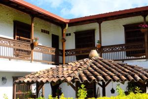 um edifício com um telhado de azulejo e uma varanda em Casa Hotel Portón Campestre em Jardin