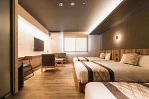 una camera d'albergo con 2 letti e una scrivania di GRAND BASE Beppu Ekihigashi a Beppu