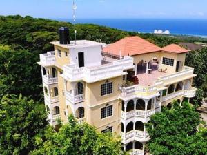 a large building on top of a hill with trees at Takuma Boutque Hotel Hotel Rooms & Suites in Montego Bay