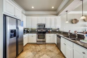 Una cocina con gabinetes blancos y un refrigerador de acero inoxidable. en Casa Del Mar, en Gulf Shores