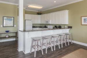 una cocina con armarios blancos y taburetes de bar en Serenity, en Gulf Shores