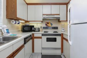 a kitchen with white cabinets and a white refrigerator at Gulf Village #215 in Gulf Shores