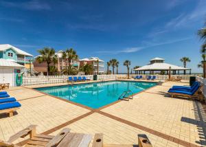 una piscina con sillas azules y palmeras en Serenity, en Gulf Shores