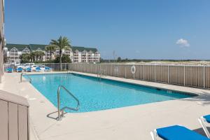 a swimming pool with chairs and a fence at Royal Palms #1006 in Gulf Shores