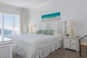 um quarto branco com uma grande cama branca e janelas em Dolphin Key em Orange Beach