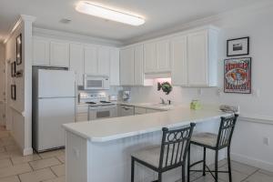uma cozinha com armários brancos e um balcão com duas cadeiras em Dolphin Key em Orange Beach