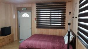 1 dormitorio con cama, ventana y puerta en Izmir Pension, en Gangneung