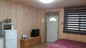a room with a bed and a refrigerator and a door at Izmir Pension in Gangneung