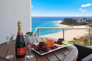 a table with a plate of fruit and a bottle of wine at ULTIQA Points North in Gold Coast