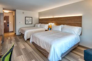 a hotel room with two beds and a chair at Holiday Inn Express & Suites Lincoln Airport by IHG in Lincoln +19 photos