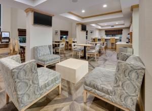 a waiting area with chairs and tables in a restaurant at Holiday Inn Express & Suites San Antonio Brooks City Base, an IHG Hotel in San Antonio