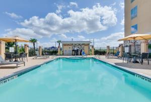 una piscina con sillas y sombrillas en un hotel en Holiday Inn Express & Suites San Antonio Brooks City Base, an IHG Hotel en San Antonio