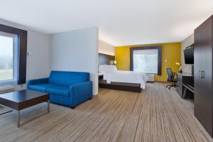 a hotel room with a bed and a blue couch at Holiday Inn Express Hotel & Suites Cleveland-Richfield by IHG in Brecksville