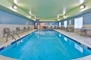 uma piscina com cadeiras e mesas num quarto de hotel em Holiday Inn Express Hotel & Suites Cleveland-Richfield, an IHG Hotel em Brecksville