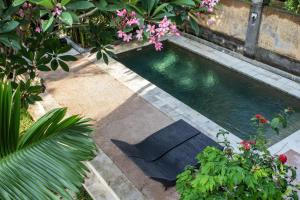 a swimming pool in a garden with flowers and plants at Balian Surf Villas in Selemadeg