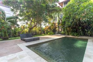 una piscina en un patio con una silla y árboles en Balian Surf Villas, en Selemadeg