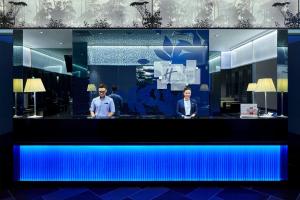 新加坡Holiday Inn Express Singapore Katong by IHG的两个人站在柜台后面,灯亮