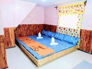 um quarto com uma cama com lençóis azuis e uma janela em Blue Lagoon Inn and Restaurant em Mabubua